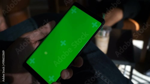 close up young business man hand holding smart phone with green screen, motion tracking,chroma key on display and touching,swipe left and right white working in cafe or coffee shop.
