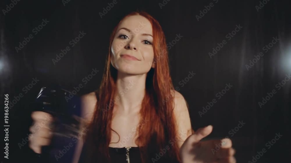 Portrait of young woman playing on the tambourine in studio on rainy background Portrait of young woman playing on the tambourine in studio on rainy background