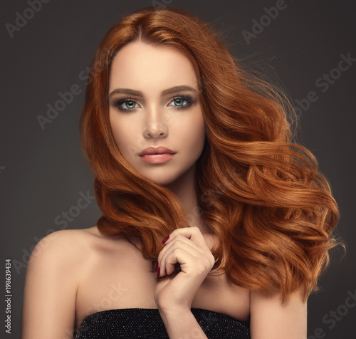 Beautiful model girl with long red curly hair .Red head . Care and beauty hair products 