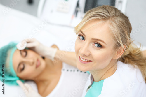 Professional beautician and young woman in beauty salon. Makeup artist touch customer skin with cotton pads, closeup. Cosmetology , facial, beauty and spa 