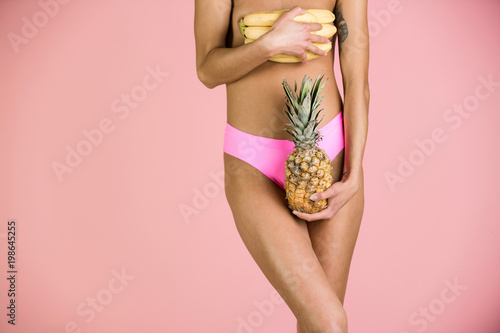 pineapple and banana in hand of girl in bikini