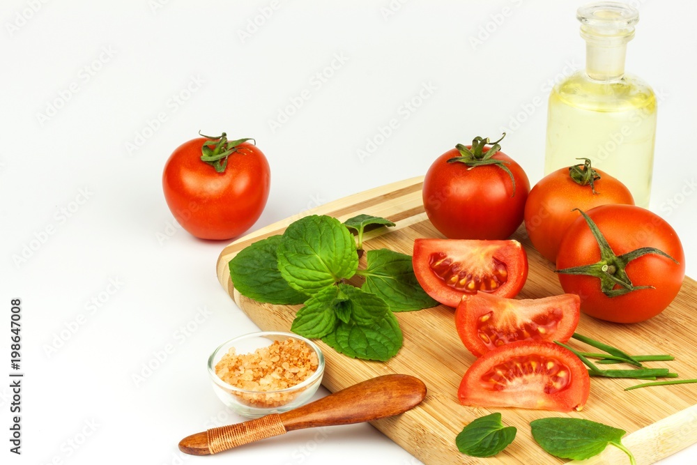 Tomatoes and herbs on a kitchen board. Preparation of healthy food. Raw vegetables. On a white background. Tomatoes and herbs on a kitchen board. Preparation of healthy food. Raw vegetables. On a white background.