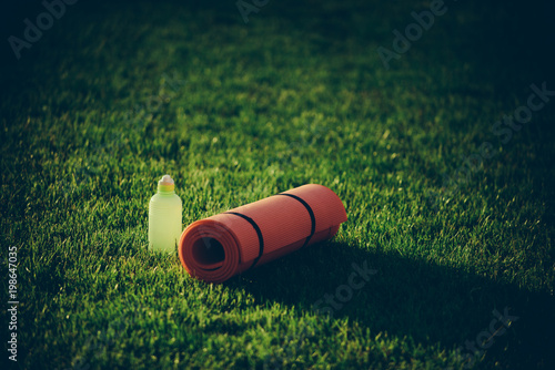 Mat and plastic bottle on green grass