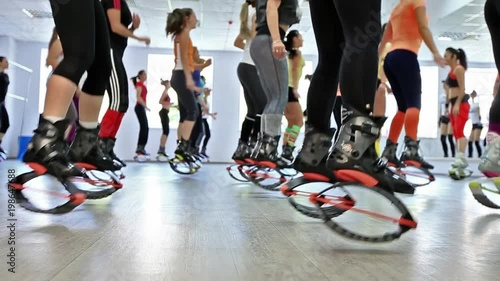 Group of young caucasian women doing fitnes exercises with kangoo jumps shoes in a gym. photo