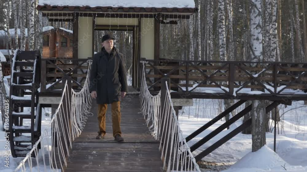 Handsome man walking on decorative bridge in winter city park slow motion Handsome man walking on decorative bridge in winter city park slow motion