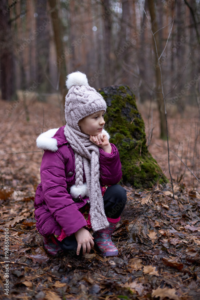 Little girl posing near the old stump in autumn forest. Little girl posing near the old stump in autumn forest.