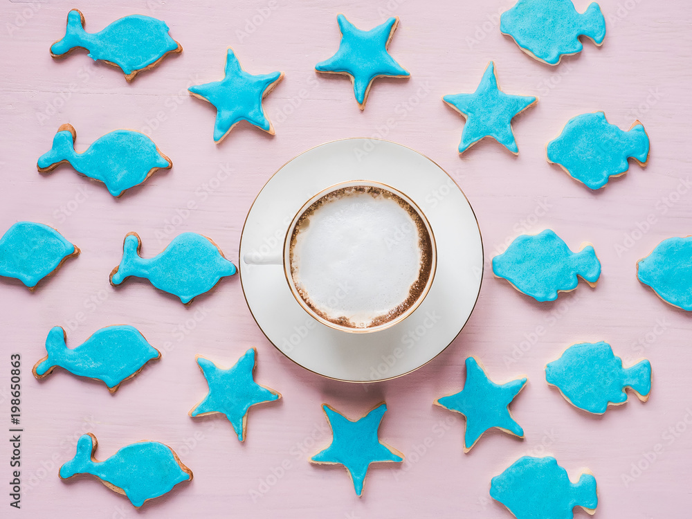 Cup with fragrant coffee and a fresh, festive cookies in blue glaze of different shapes on a pink background. Top view of a close-up. Holiday, romance, beauty