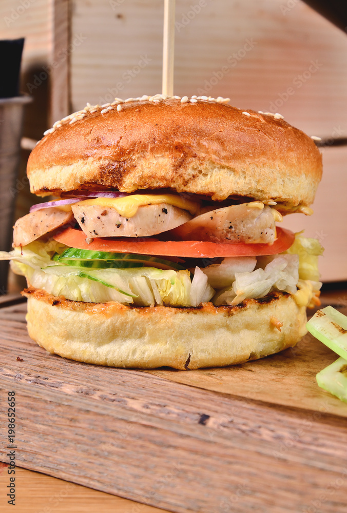Top view Fresh homemade burger with chicken, salad, cheese, onion, cucumber, tomato, sause and dark beer on a wooden board, table background. Juicey gourmet roll bread, fast food concept. Text place Top view Fresh homemade burger with chicken, salad, cheese, onion, cucumber, tomato, sause and dark beer on a wooden board, table background. Juicey gourmet roll bread, fast food concept. Text place