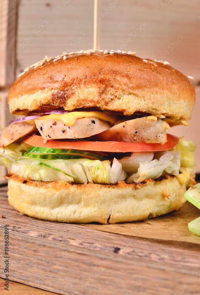 Top view Fresh homemade burger with chicken, salad, cheese, onion, cucumber, tomato, sause and dark beer on a wooden board, table background. Juicey gourmet roll bread, fast food concept. Text place Top view Fresh homemade burger with chicken, salad, cheese, onion, cucumber, tomato, sause and dark beer on a wooden board, table background. Juicey gourmet roll bread, fast food concept. Text place