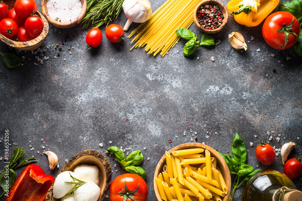 Italian food background. Pasta, herbs, vegetables on black top v Italian food background. Pasta, herbs, vegetables on black top v