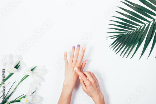 Woman applying hand cream among tropical flowers