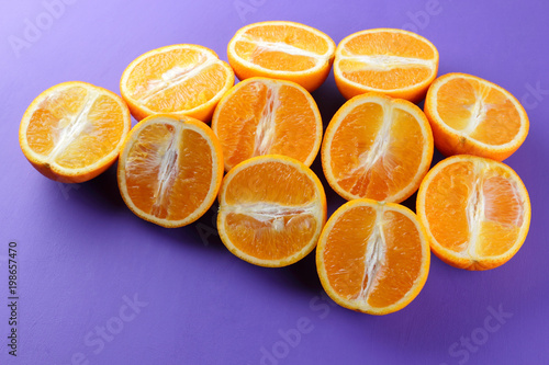 Fruit oranges on a purple background, a lot of orange halves for vegan, sliced citrus fruits for breakfast, fruit pop art pattern, vitamin set designer, juicy orange fruit