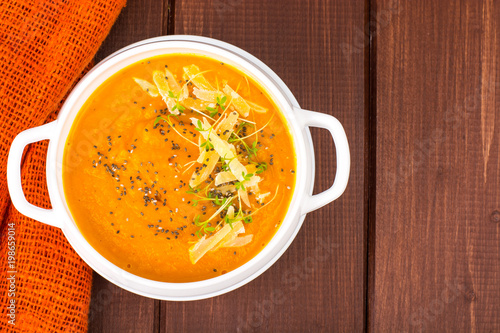 Pumpkin carrot cream soup with parmesan and green shoots of watercress