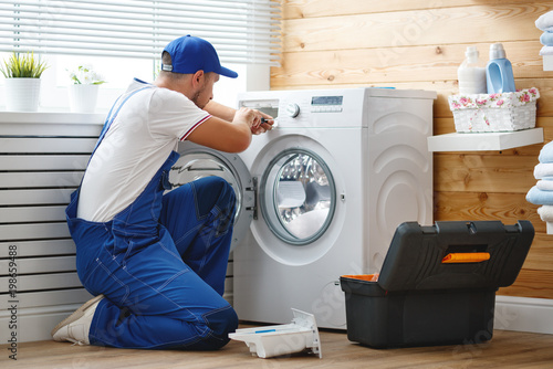 working man   plumber repairs  washing machine in   laundry.