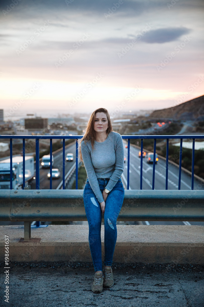 attractive young woman posing on a bridge above of the road attractive young woman posing on a bridge above of the road