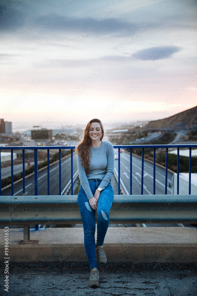 attractive young woman posing on a bridge above of the road attractive young woman posing on a bridge above of the road