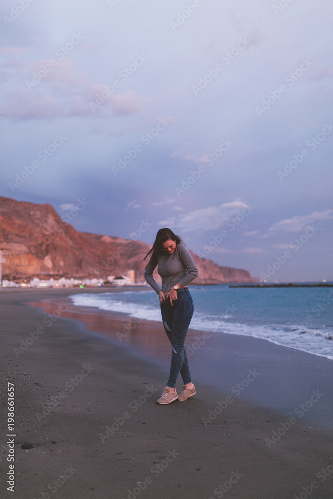 Attractive happy young woman posing on the beach in a nice sunset