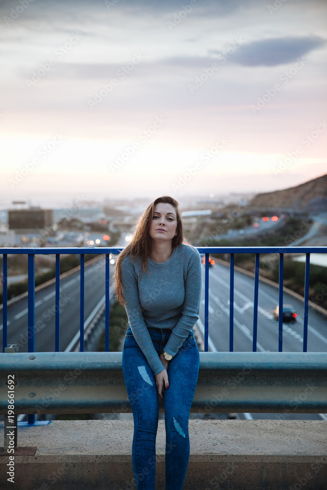 attractive young woman posing on a bridge above of the road attractive young woman posing on a bridge above of the road