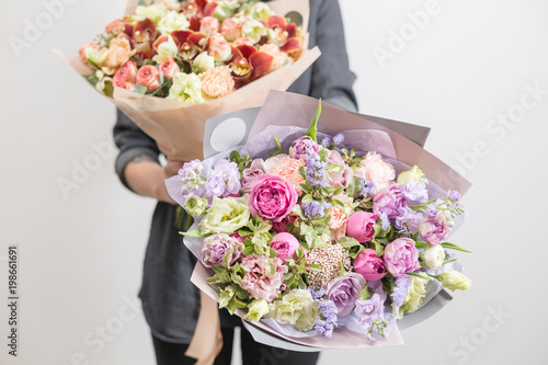 Fototapeta Naklejka Na Ścianę i Meble -  two beautiful luxury bouquet of mixed flowers in woman hand. the work of the florist at a flower shop. A small family business