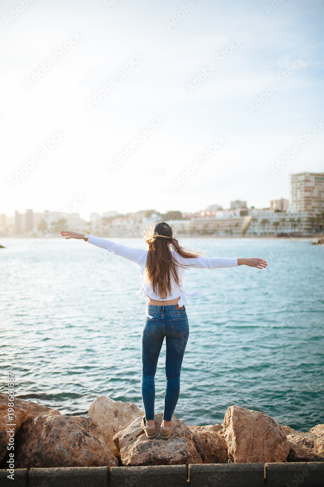 Attractive young woman posing with a cap in marina in the sunset