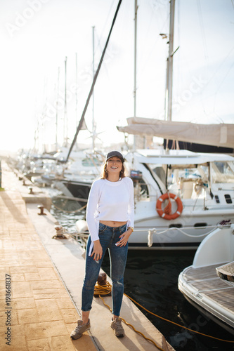 Attractive young woman posing with a cap in marina in the sunset