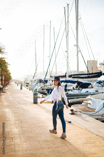 Attractive young woman posing with a cap in marina in the sunset