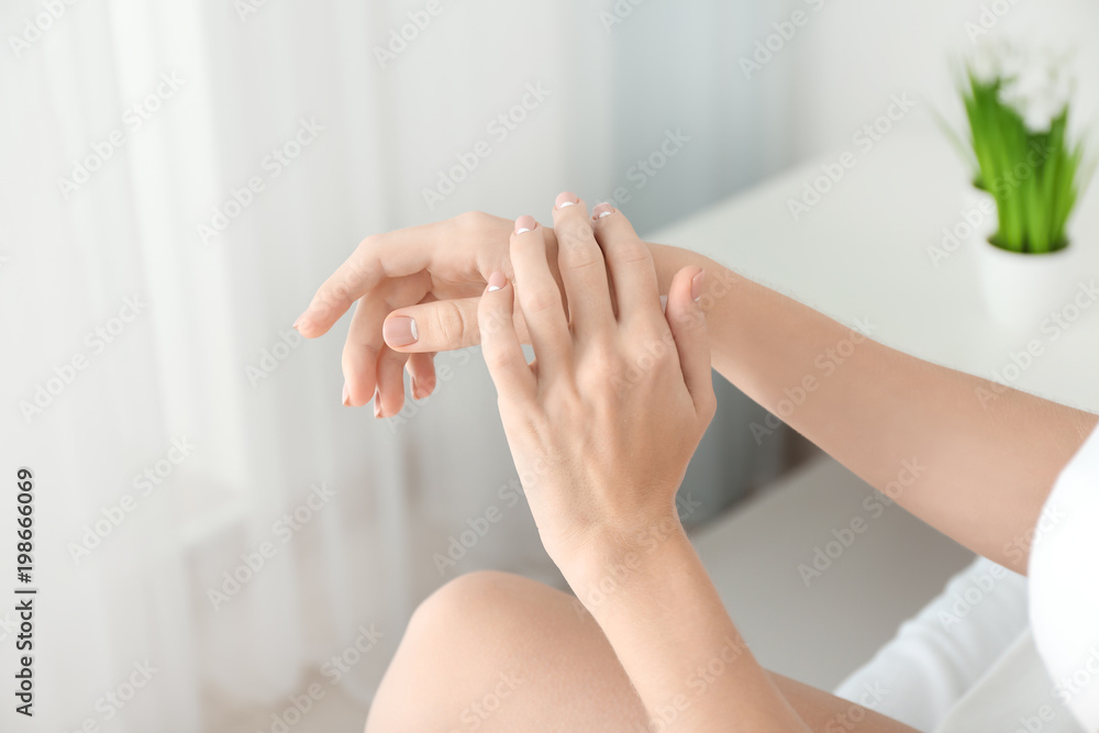 Young woman applying hand cream at home Young woman applying hand cream at home