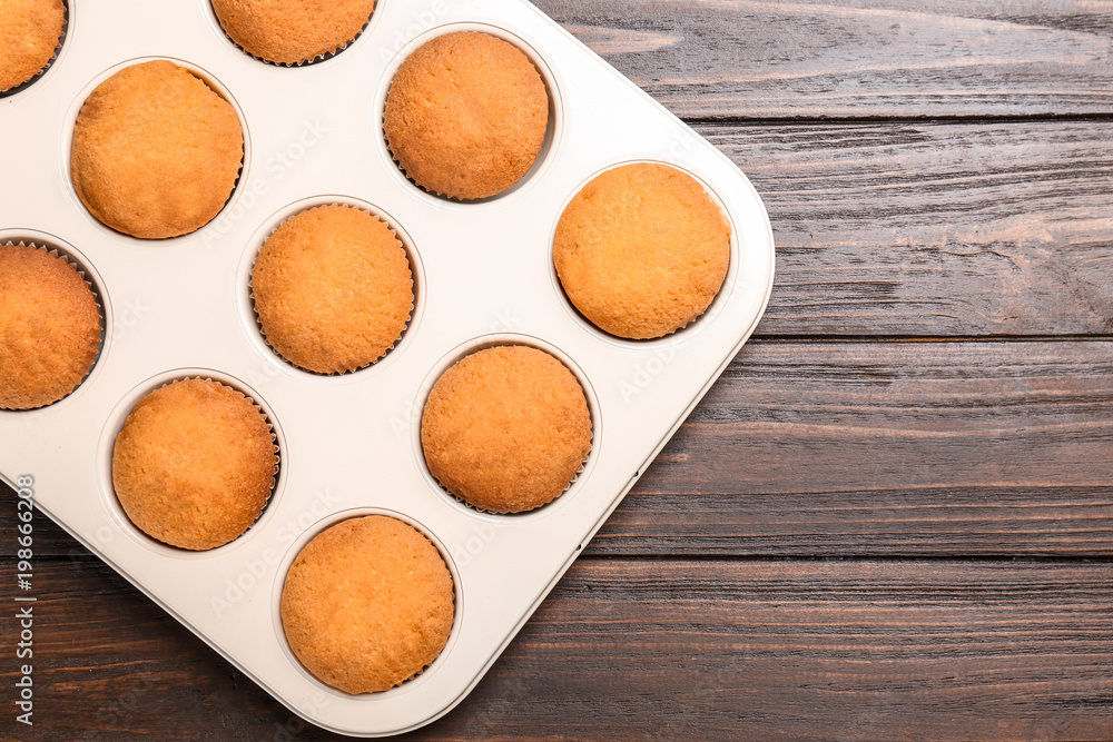 Baking tray with tasty cupcakes on wooden background. Fresh from oven Baking tray with tasty cupcakes on wooden background. Fresh from oven