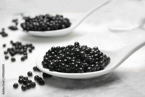 Spoons with delicious black caviar on marble board