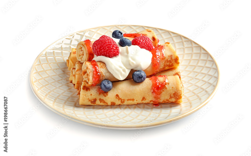 Thin pancakes with syrup, cream and berries on plate against white background Thin pancakes with syrup, cream and berries on plate against white background