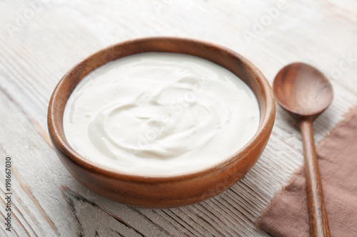 Bowl with tasty yogurt on wooden table