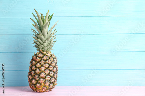 Fresh pineapple on table against color wall