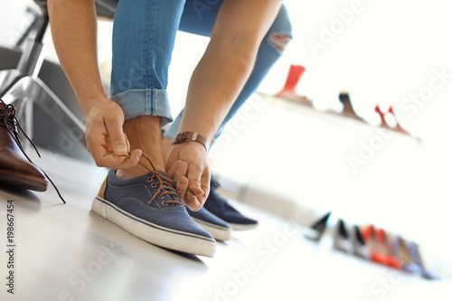 Young man trying on shoes in store
