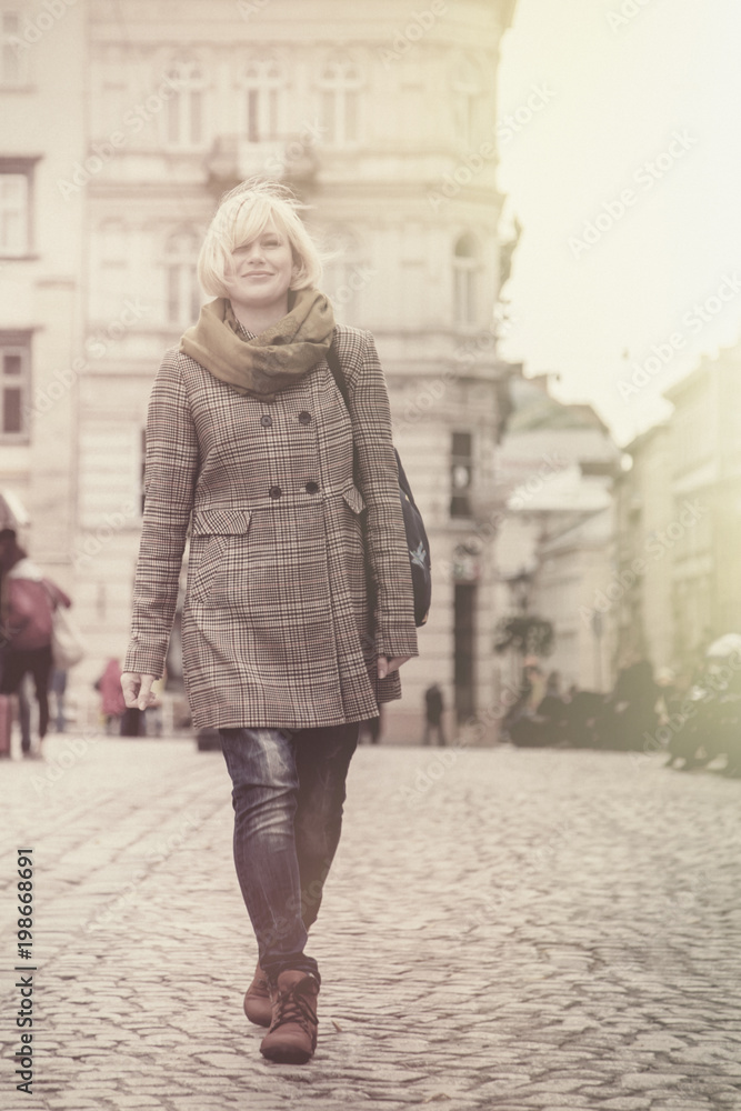 Travel is the secret of happiness. Beautiful blonde woman walking Europe city streets. Holiday, vacation, adventure, positive emotions concept.