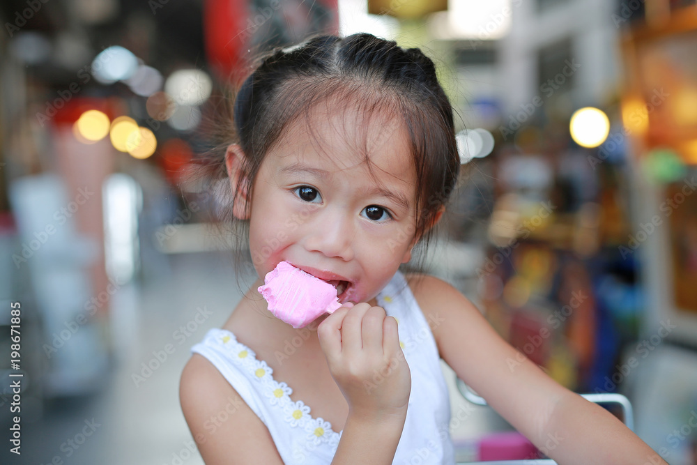 Cute little asian child girl eating ice-cream.
