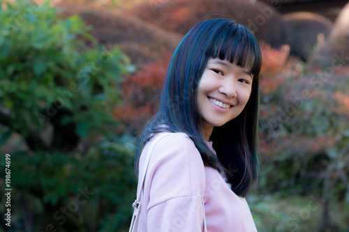 Portrait of beautiful young asian woman with blue and green hair in a japanese garden