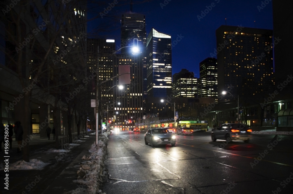 Toronto downtown street view with cars headlamps reflection on wet asphalt
