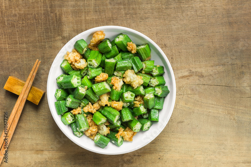 stir-fried okra with salt in a ceramic dish on wooden table. homemade style healthy food concept.