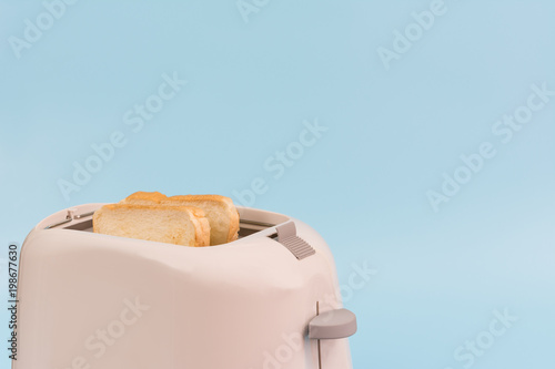 crunchy and hot toast in a toaster on light blue background with copy space. breakfast concept.
