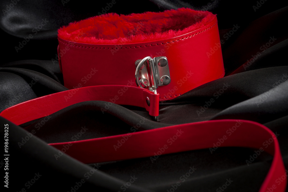 Fotka „BDSM kink, erotic dom / sub sex games, kinkwear and deviant sexual  behaviour concept with close up on a kinky collar with a red leather leash  attached on dark black silk