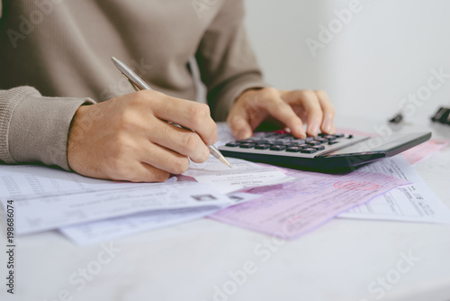 Hand man doing finances and calculate on desk about cost at home office.