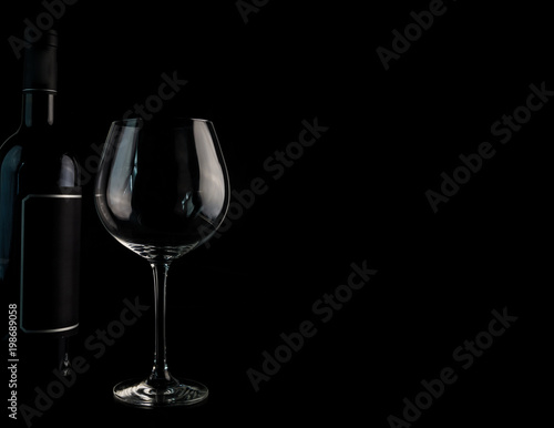 Weinflasche mit einem Weinglas gegen einen schwarzen Hintergrund. Enthält einen Textfreiraum für eigenen Text.