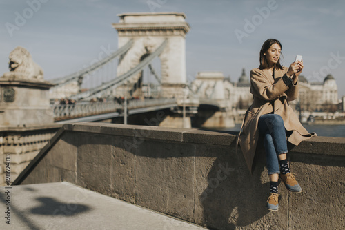 Young woman using mobile phone with Chain bridge at background in Budapest © BGStock72
