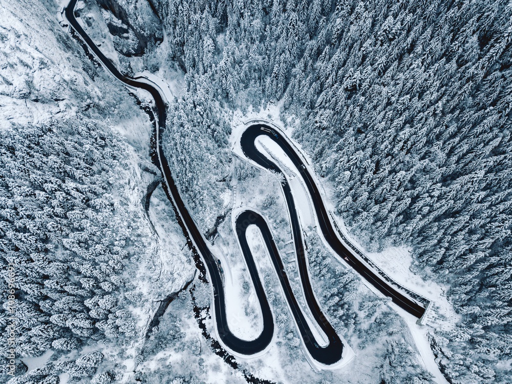 Aerial view of snowy forest with a road. Captured from above with a drone
