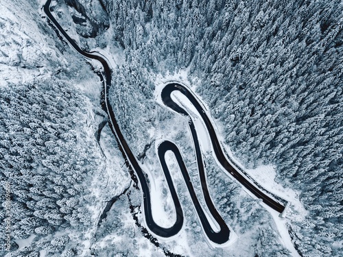 Aerial view of snowy forest with a road. Captured from above with a drone © szaboerwin