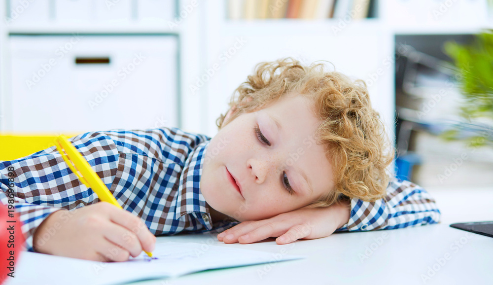 Tired little boy sitting at the table, with hishead on his arm, Tired little boy sitting at the table, with hishead on his arm,