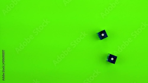 Blue casino dice being rolled and settling on craps (double one) on a green screen. Multiple rolls