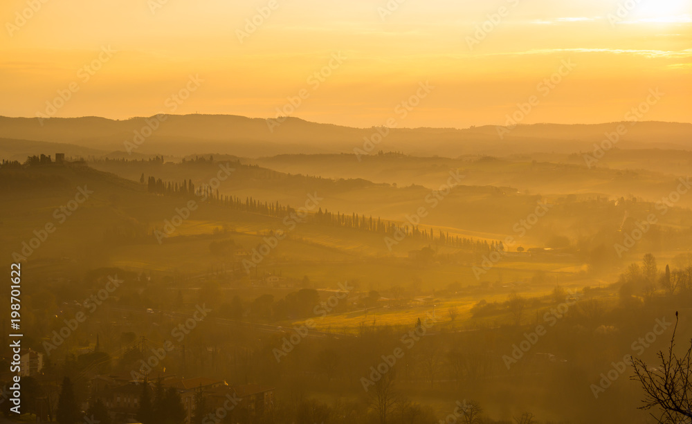 Obraz premium Sunrise in the lands of Tuscany. Warm colors on the hills and haze