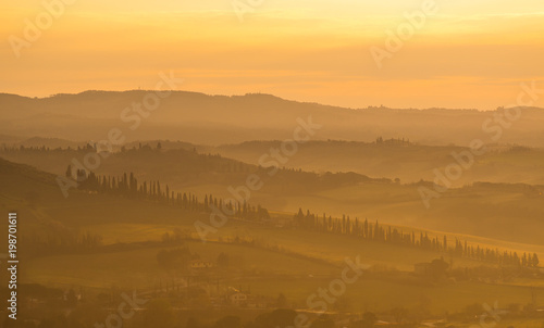Fototapeta Naklejka Na Ścianę i Meble -  Sunrise in the lands of Tuscany. Warm colors on the hills and haze