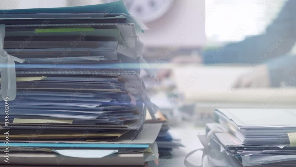 Employee working in the office and piles of paperwork Employee working in the office and piles of paperwork